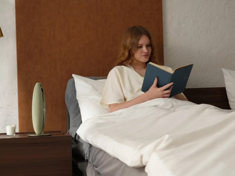 Person reading in bed beside LunaWake before sleep